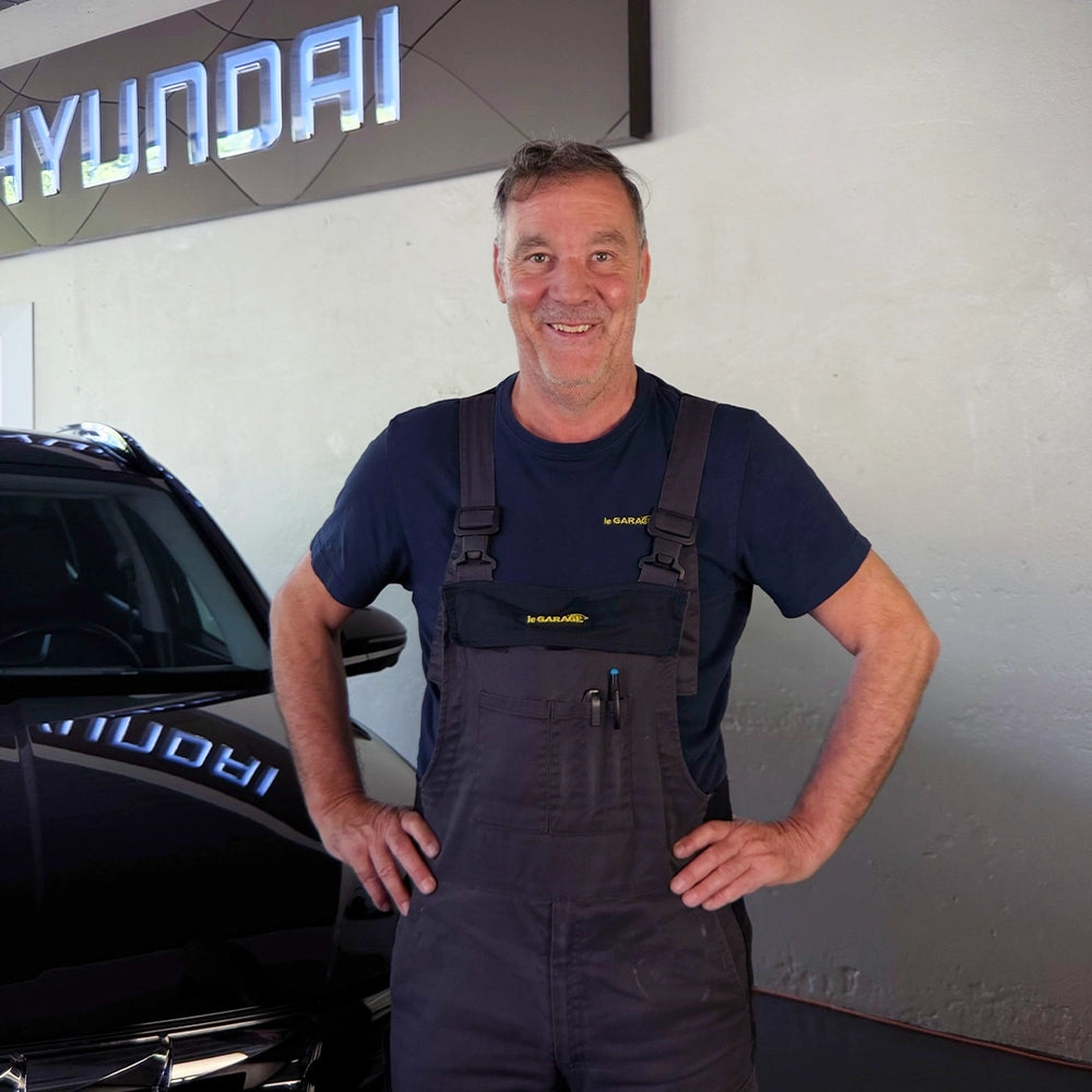 Andreas Brünisholz von der Touring Garage Brünisholz in Escholzmatt im le GARAGE Arbeitsoverall vor dem Hyundai-Logo.