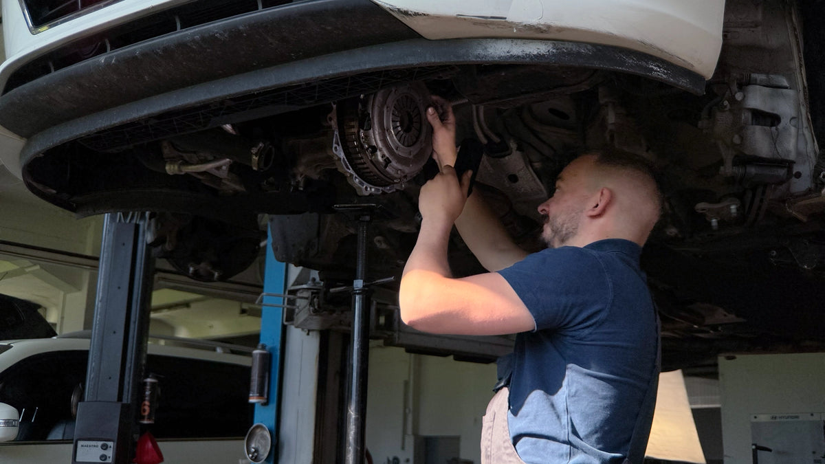 Autofachmann der Touring Garage Brünisholz in Escholzmatt bei der mechanischen Reparatur eines Autos auf der Hebebühne.