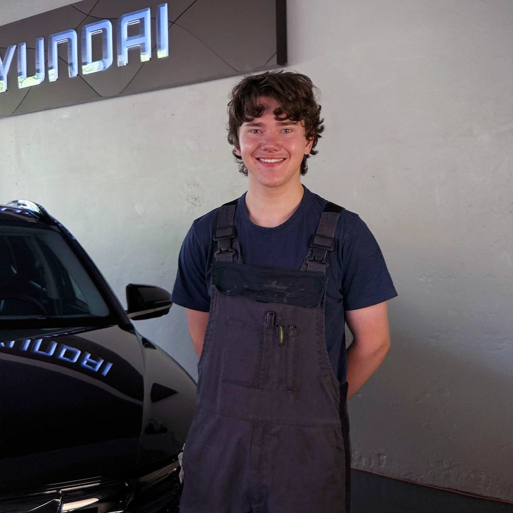 Sven Riedweg von der Touring Garage Brünisholz in Escholzmatt im dunklen le GARAGE Arbeitsoverall vor dem Hyundai-Logo.